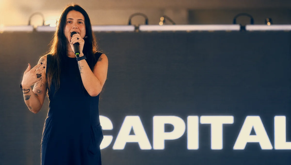 Alma gesticula enquanto apresenta CAPITALIPSE no palco